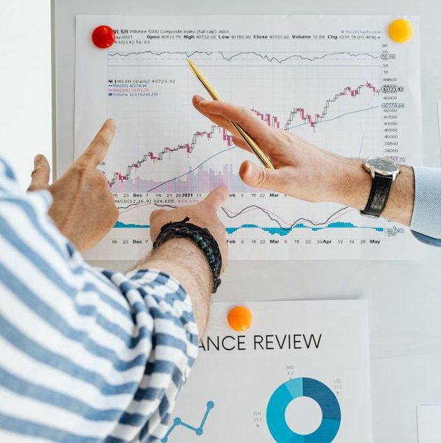 Two people analyzing financial charts on a whiteboard during a business meeting.